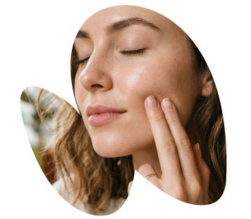 Close-up of a woman with healthy, glowing skin touching her cheek